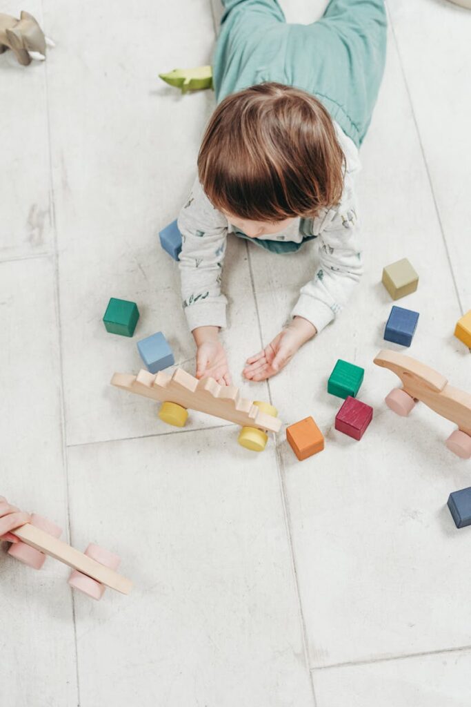 Photo by cottonbro studio Child playing with colorful wooden toys on a light floor, creating a fun and educational setting.