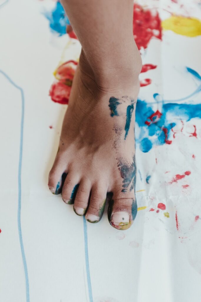 Photo by Bernard Hermant person his right foot painting on white paper